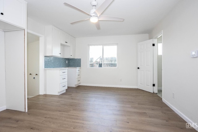 interior space featuring white cabinetry, ceiling fan, decorative backsplash, and light hardwood / wood-style flooring