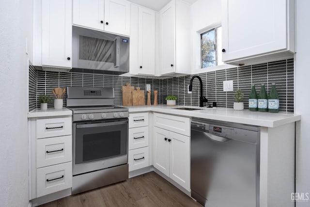 kitchen featuring appliances with stainless steel finishes, dark hardwood / wood-style floors, tasteful backsplash, white cabinetry, and sink