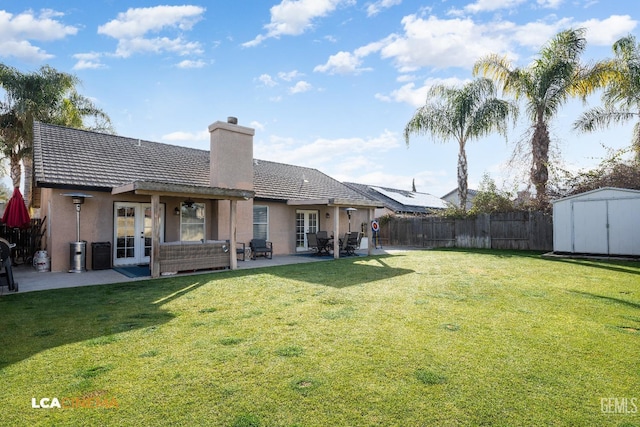 rear view of house with a shed, a patio area, and a lawn