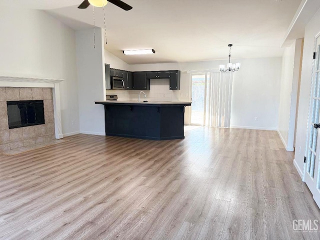 5717 Arc Dome Ave, Bakersfield, CA 93313 - kitchen with light wood-style flooring, ceiling fan, a kitchen bar, dark cabinetry, and open floor plan