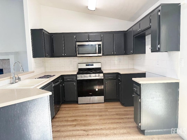 5717 Arc Dome Ave, Bakersfield, CA 93313 - kitchen featuring stainless steel appliances, vaulted ceiling, light wood-style flooring, decorative backsplash, and light countertops
