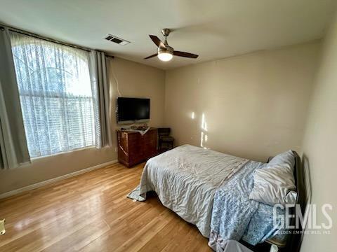 bedroom featuring baseboards, light wood-style flooring, visible vents, and a ceiling fan