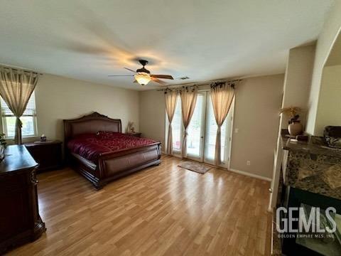 bedroom with access to outside, a fireplace, visible vents, ceiling fan, and light wood-type flooring