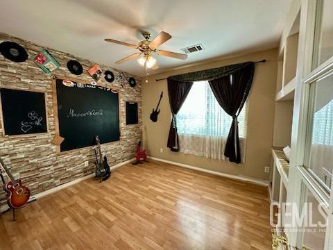 interior space with baseboards, wood finished floors, visible vents, and a ceiling fan