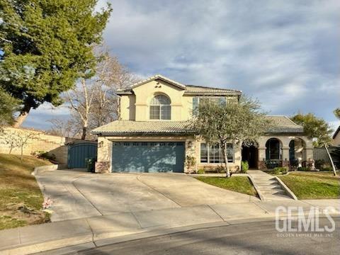 mediterranean / spanish house featuring concrete driveway, a tile roof, an attached garage, a gate, and stucco siding