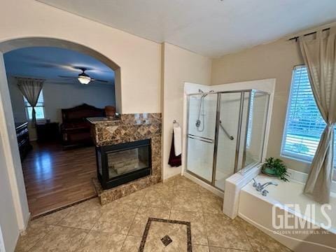 bathroom with a stall shower, a fireplace, a garden tub, and a wealth of natural light