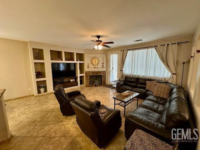 tiled living room featuring ceiling fan, a fireplace, visible vents, and built in features