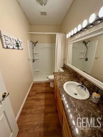 bathroom featuring baseboards, toilet, wood finished floors, curtained shower, and vanity