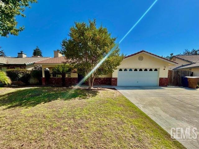 single story home featuring a garage and a front lawn