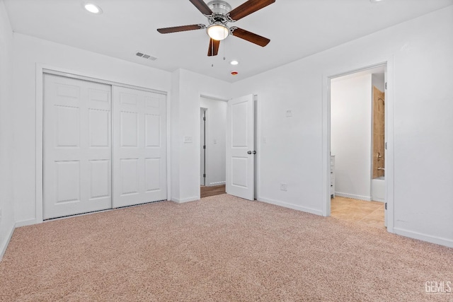 unfurnished bedroom featuring ceiling fan, a closet, connected bathroom, and light carpet