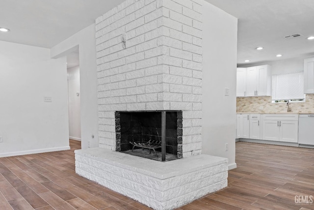 details featuring hardwood / wood-style flooring, a fireplace, white dishwasher, and tasteful backsplash