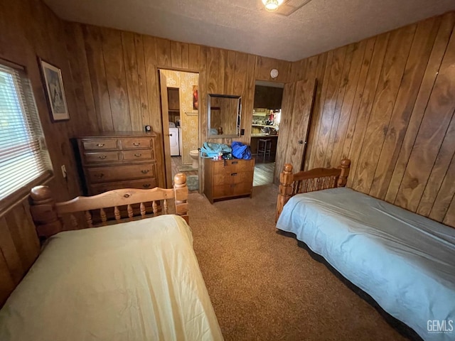 carpeted bedroom featuring washer / dryer, a textured ceiling, and wood walls