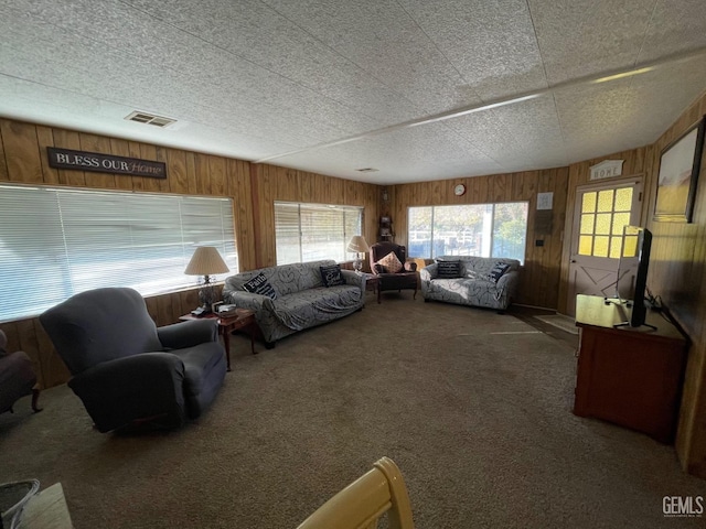 living area with carpet, visible vents, and wooden walls