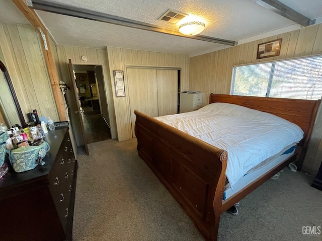 bedroom with beam ceiling, a closet, light colored carpet, visible vents, and wooden walls