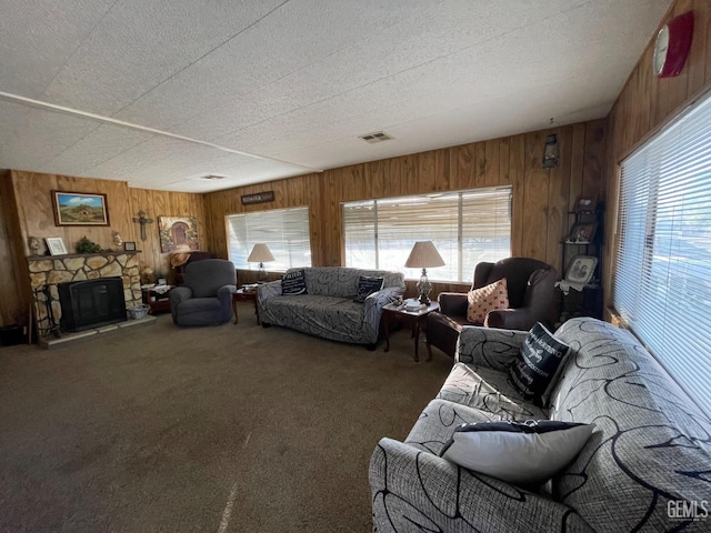 living room with a stone fireplace, carpet flooring, visible vents, and a healthy amount of sunlight