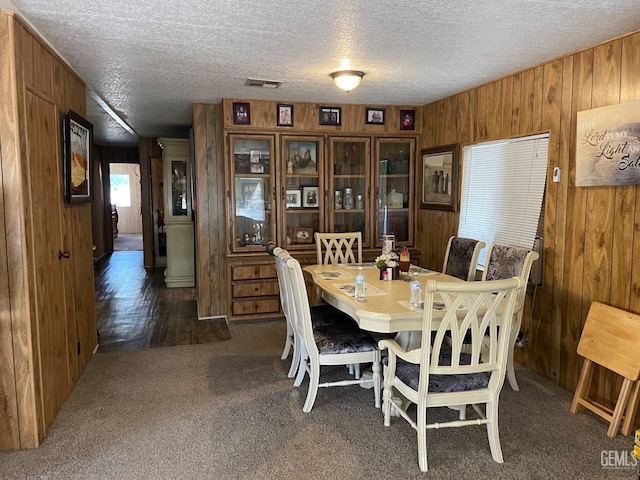 dining room featuring carpet, visible vents, and wooden walls