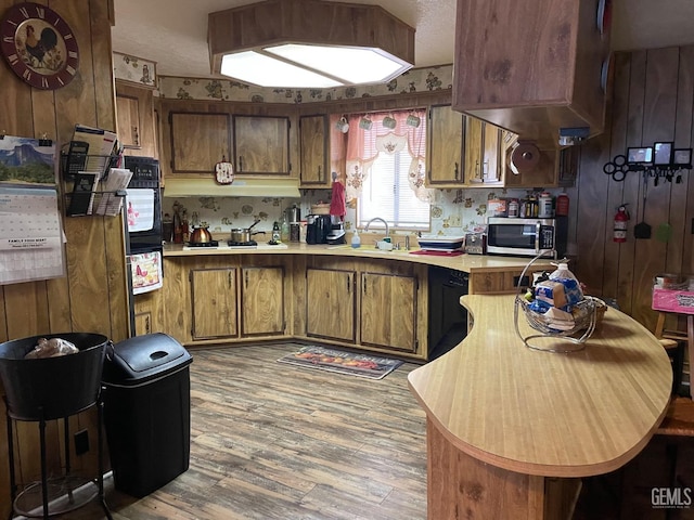 kitchen with oven, light wood-style flooring, a sink, light countertops, and stainless steel microwave