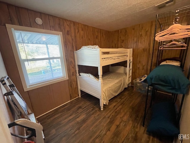 bedroom featuring wood walls and dark wood finished floors