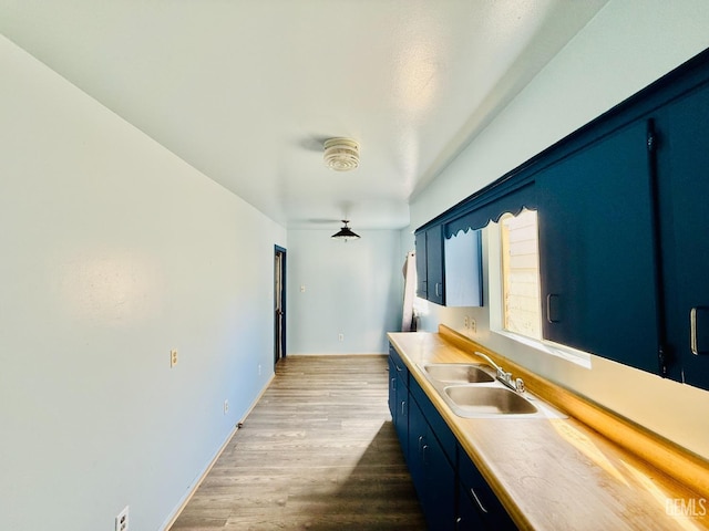 kitchen with dark wood finished floors, light countertops, a sink, blue cabinets, and baseboards