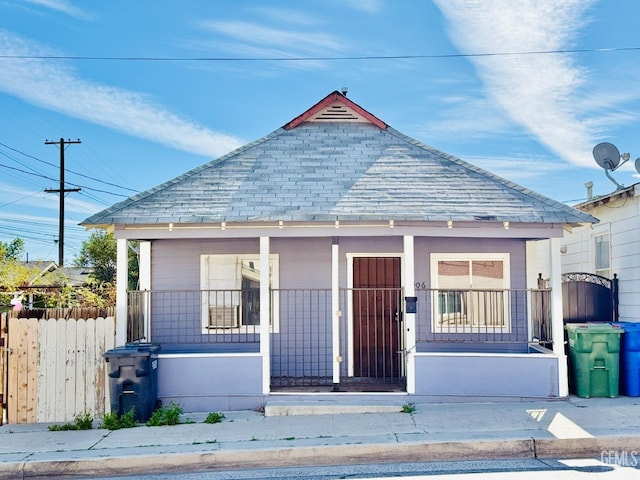 bungalow-style house featuring a porch, roof with shingles, and fence