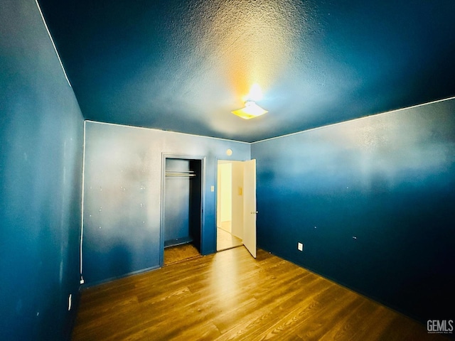 unfurnished bedroom featuring a closet, a textured ceiling, and wood finished floors