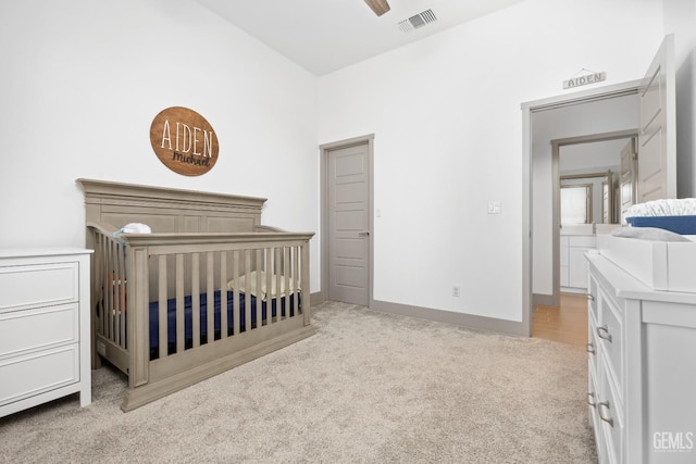 bedroom with light colored carpet, visible vents, a ceiling fan, a nursery area, and baseboards