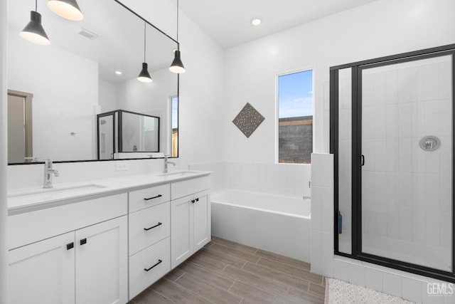 full bathroom featuring visible vents, a sink, a shower stall, and a garden tub