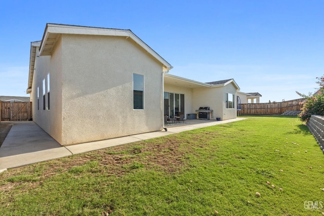 rear view of property featuring a lawn, a patio area, a fenced backyard, and stucco siding