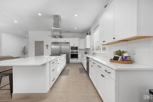 kitchen featuring built in appliances, light countertops, white cabinets, and a center island