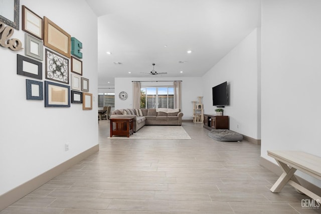 living room featuring baseboards, light wood-type flooring, a ceiling fan, and recessed lighting