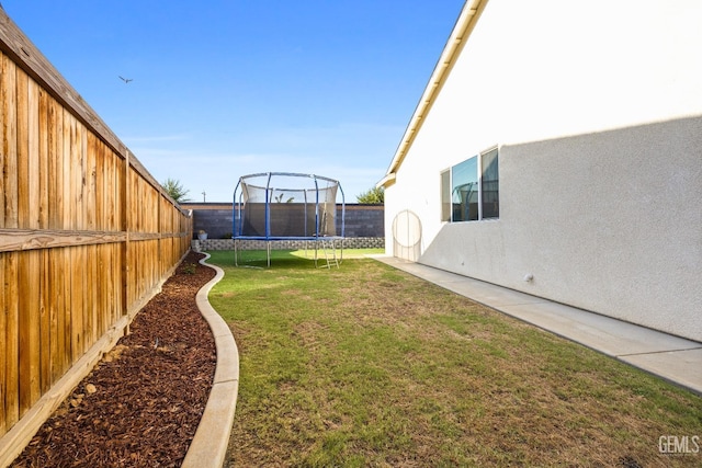 view of yard featuring a trampoline and a fenced backyard