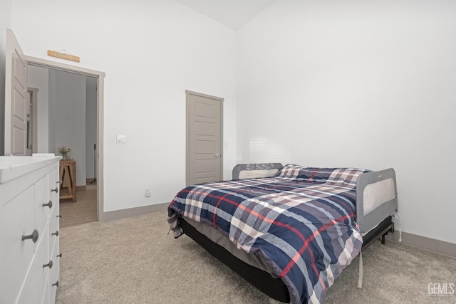 bedroom with baseboards, high vaulted ceiling, and light colored carpet