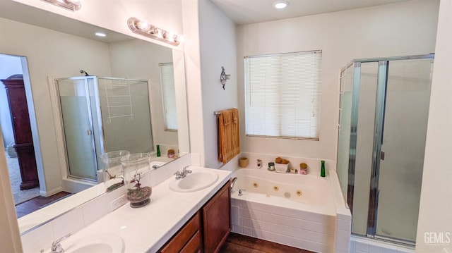full bath with double vanity, a jetted tub, a sink, and a stall shower