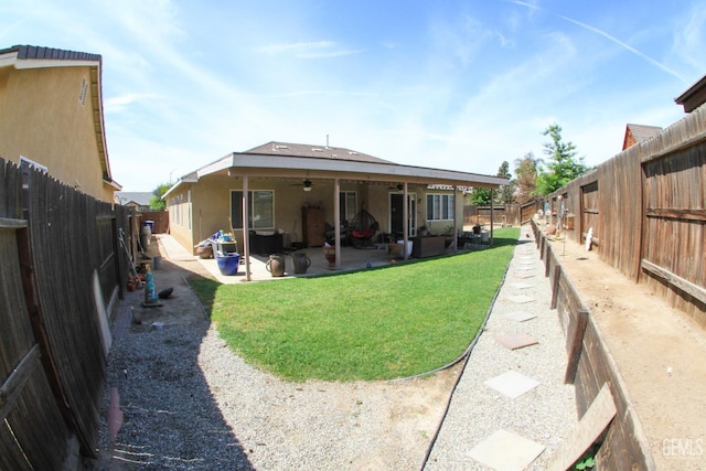 back of property with a patio area, a fenced backyard, a ceiling fan, and a lawn