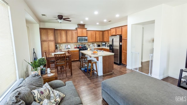 kitchen with a breakfast bar, light countertops, a ceiling fan, visible vents, and stainless steel appliances