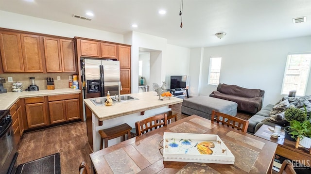 kitchen featuring stainless steel fridge with ice dispenser, visible vents, light countertops, and brown cabinets