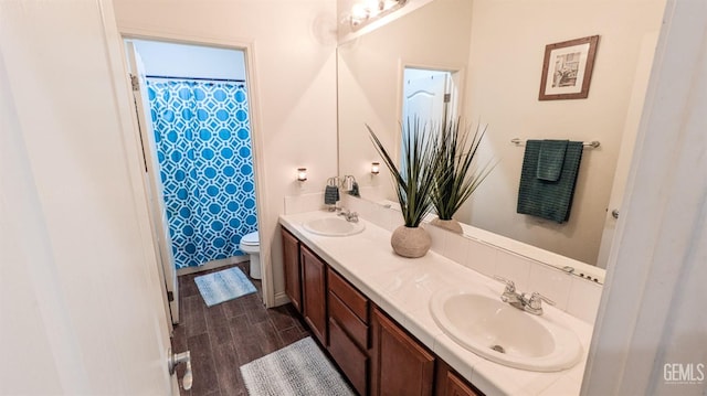 full bathroom featuring double vanity, a sink, toilet, and wood finished floors