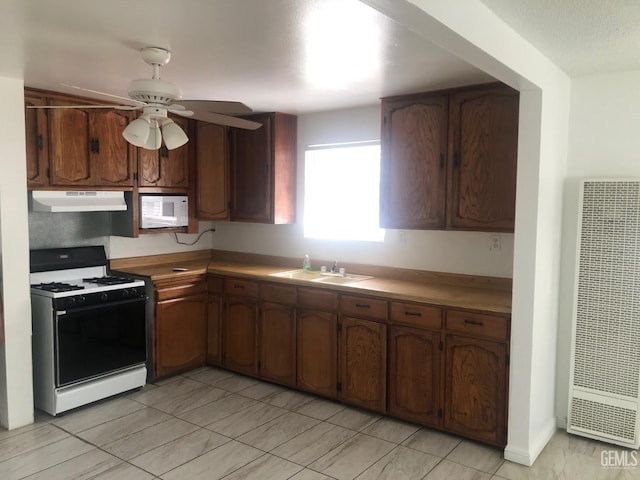 1543 Sycamore Dr, Wasco, CA 93280 - kitchen featuring a heating unit, range with gas cooktop, under cabinet range hood, white microwave, and a sink