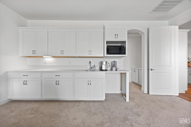 kitchen with sink, white cabinets, and light colored carpet