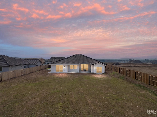 back house at dusk with a lawn