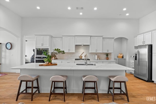 kitchen featuring a kitchen island with sink, white cabinets, and appliances with stainless steel finishes