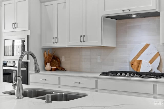 kitchen featuring light stone countertops, decorative backsplash, sink, white cabinetry, and stainless steel gas stovetop