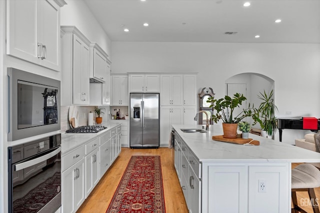 kitchen featuring white cabinetry, sink, a kitchen bar, a center island with sink, and appliances with stainless steel finishes