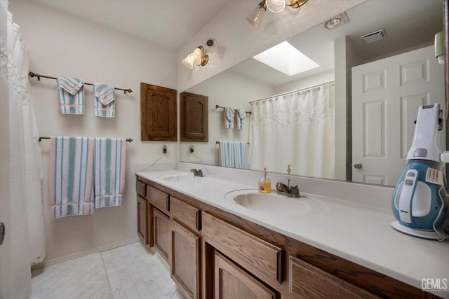 bathroom with a skylight, double vanity, tile patterned floors, and baseboards