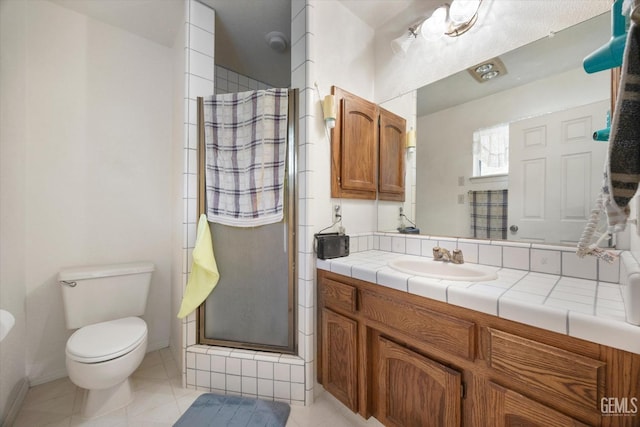 bathroom with a stall shower, vanity, toilet, tile patterned floors, and baseboards