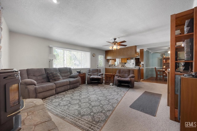 living area featuring ceiling fan, a textured ceiling, and light carpet