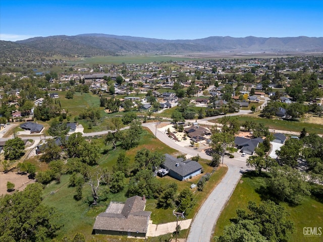 aerial view of property and surrounding area featuring a mountain backdrop and nearby suburban area