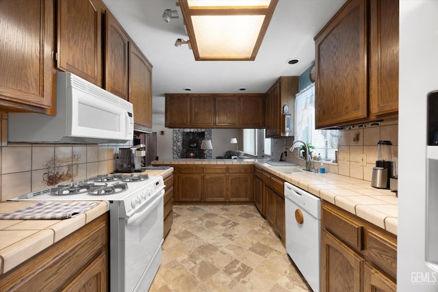 kitchen featuring white appliances, a sink, tile countertops, and tasteful backsplash