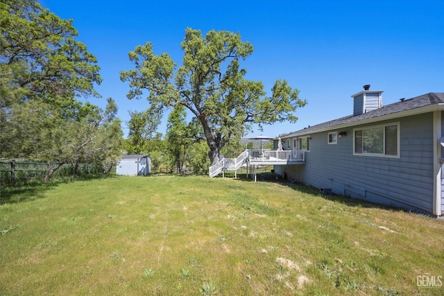 view of yard featuring a deck, an outdoor structure, a storage unit, and stairs