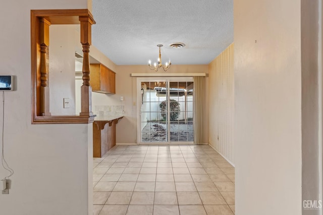 unfurnished dining area featuring a notable chandelier, a textured ceiling, and light tile patterned floors